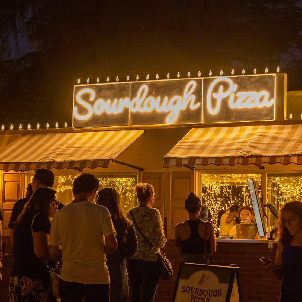 Guests lined up at the Sourdough Pizza booth at night