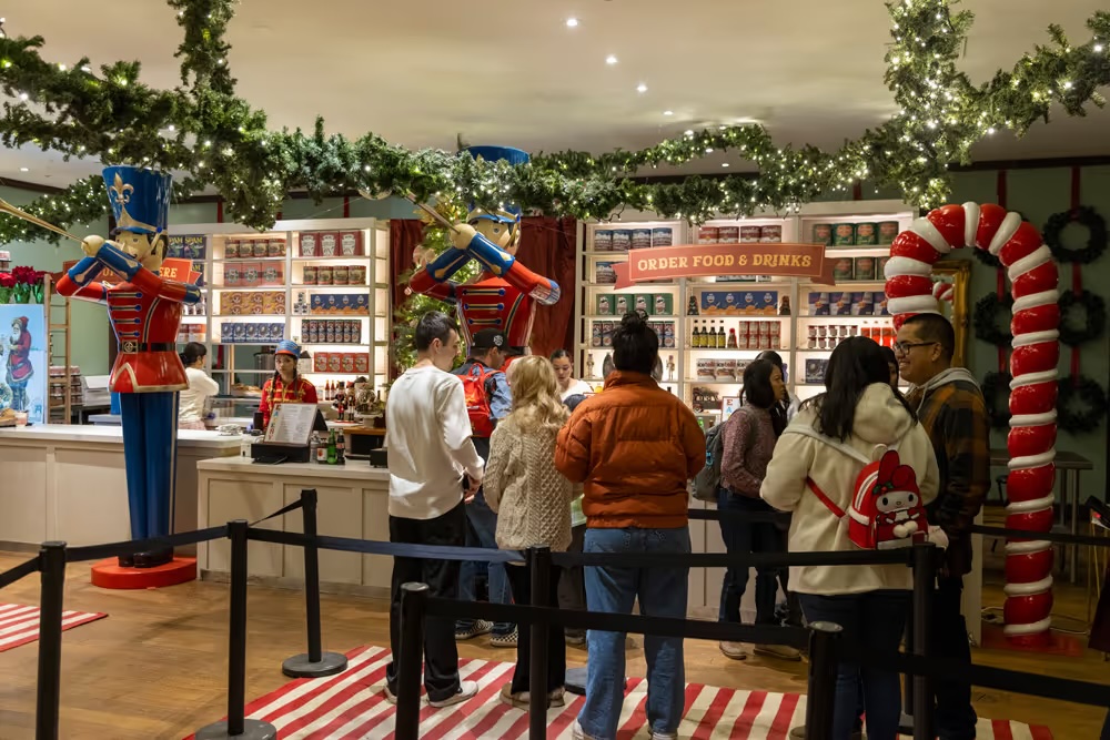 Guests ordering under the Order Food & Drinks sign beside toy soldiers at the Nutcracker Eatery